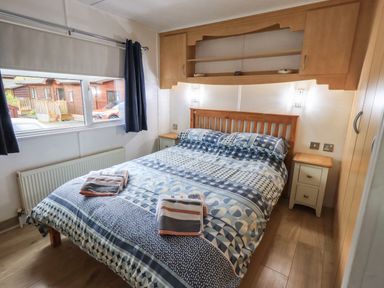 A bedroom with a double bed next to a window and wooden cabinets at Lavender Lodge Applethwaite 4 Limefitt Park near Windermere