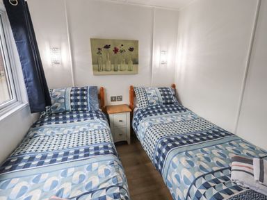 A bedroom with two single beds with blue patterned bedding and a small nightstand between them at Lavender Lodge in Applethwaite 4 Limefitt Park near Windermere