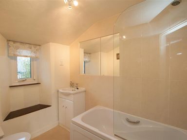 A bathroom with a bathtub a sink a small window and a mirror at Rustic Cottage in Bowness-On-Windermere