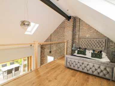 A bedroom loft with a bed and two side tables next to a brick wall at Kaitkyella Lodge in Scarborough