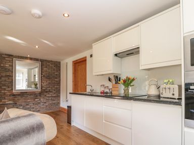 A kitchen area with white cabinets black countertop a kettle toaster and flowers on the counter at Kaitkyella Lodge in Scarborough