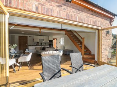 An open plan living area with a kitchen lounge dining space and wooden stairs at Kaitkyella Lodge in Scarborough