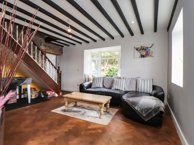 A living room with a black sofa and coffee table at Tyddyn Elidir near Old Colwyn