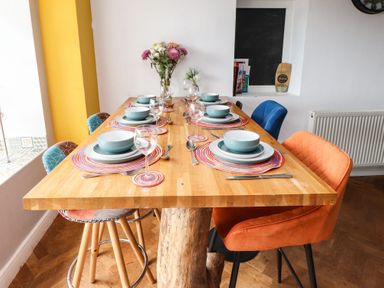 A dining room with a wooden table set for a meal at Tyddyn Elidir near Old Colwyn