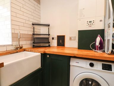 A laundry room with a sink and washing machine at Tyddyn Elidir near Old Colwyn