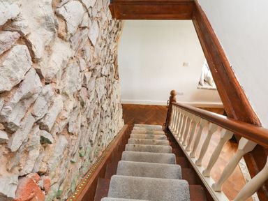 Stairs with a wooden handrail and stone wall at Tyddyn Elidir near Old Colwyn