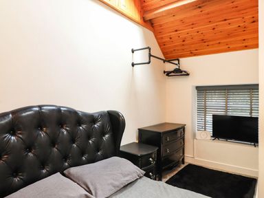 A bedroom with a bed, dresser, and television at Tyddyn Elidir near Old Colwyn