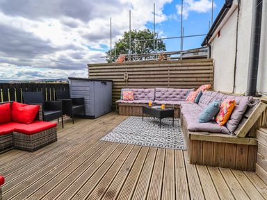 An outdoor area with cushioned seating and a coffee table at Tyddyn Elidir near Old Colwyn
