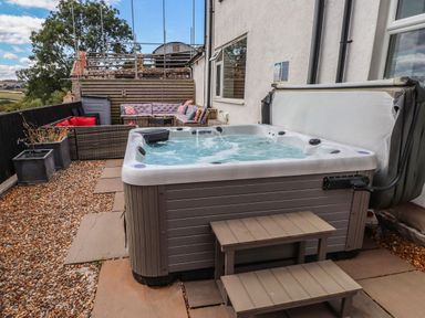 An outdoor area with a hot tub and seating at Tyddyn Elidir near Old Colwyn