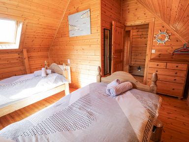 A bedroom with two wooden beds and towels on beds at Sun View Lodge in Llanbedr
