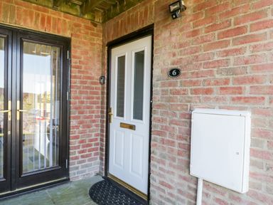 A front door with a mail slot and adjacent glass double doors on a brick wall at Esk View in Whitby
