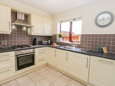 A kitchen with cream cabinets black countertops a gas stove oven and a window at Esk View in Whitby