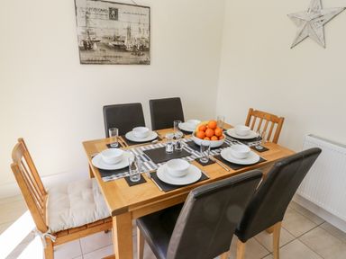 A dining table set with six place settings bowls plates glasses cutlery and a bowl of fruit at Esk View in Whitby