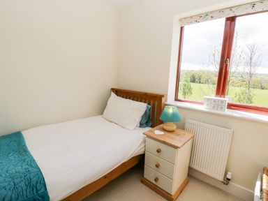 A bedroom with a single bed beside a wooden three-drawer nightstand and a window showing an outdoor view at Esk View Whitby
