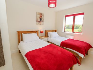 A bedroom with two single beds a window and a nightstand with a lamp at Esk View in Whitby