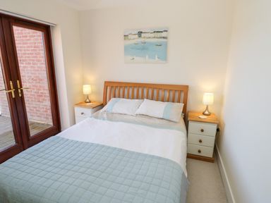 A bedroom with a double bed with bedside tables and lamps and a glass door at Esk View in Whitby