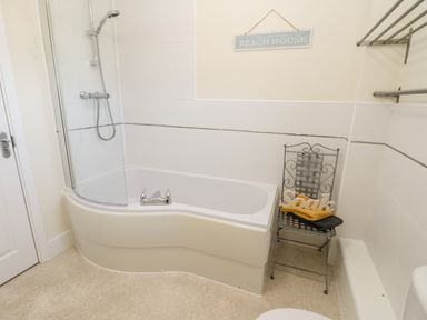 A bathroom with a bathtub shower combination and a metal chair with towels and a soak sign at Esk View in Whitby