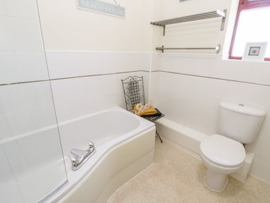 A bathroom with a bathtub a toilet a metal chair and a towel rack at Esk View in Whitby
