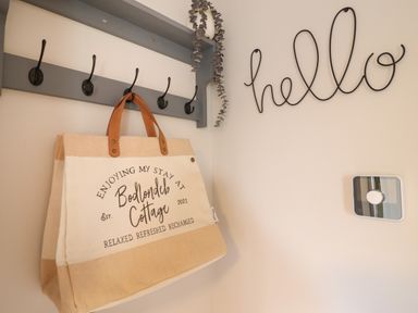 A bag hanging on a wall hook underneath a shelf next to a hello sign on the wall at Bodlondeb in Tremadog