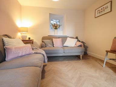 A living room with two sofas a small wooden table with a lamp and cushions at Bodlondeb in Tremadog