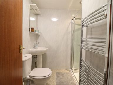 A bathroom with a toilet sink shower enclosure and towel rack at Bodlondeb in Tremadog