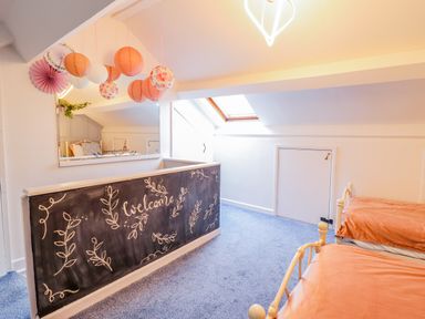 A bedroom with two single beds and a chalkboard wall with welcome message at Bodlondeb in Tremadog