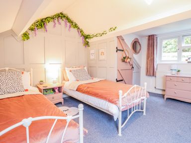 A bedroom with two single beds a nightstand a dresser and a small window at Bodlondeb in Tremadog