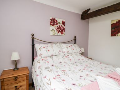 A bedroom with a double bed floral bedding bedside tables and lamps at Lavender Cottage in Penruddock