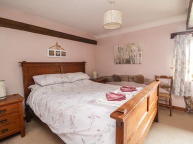A bedroom with a wooden bed and bedside tables with lamps at Daisy Cottage in Penruddock