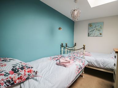 A bedroom with two single beds and floral bedding at Daisy Cottage in Penruddock