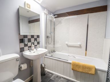 A bathroom with a toilet sink and bathtub with shower at Daisy Cottage in Penruddock