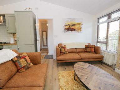 A living room with two brown sofas a wooden coffee table and large window at Broad Oak Lodge Applethwaite 7 Limefitt Park near Windermere