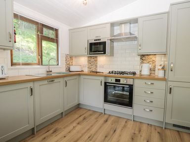 A kitchen with grey cabinets wooden countertops and a window at Broad Oak Lodge Applethwaite 7 Limefitt Park near Windermere