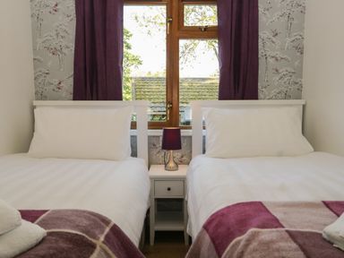 A bedroom with two single beds separated by a nightstand with a lamp at Broad Oak Lodge Applethwaite 7 Limefitt Park near Windermere