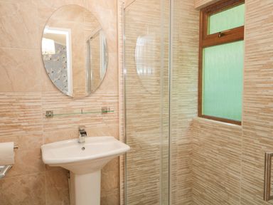 A bathroom with a pedestal sink an oval mirror a glass shelf a window and a shower at Broad Oak Lodge Applethwaite 7 Limefitt Park near Windermere