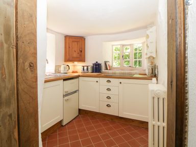A small kitchen with white cabinets wooden countertops and a window at The Hideaway at Burrow Hill in Ottery St Mary