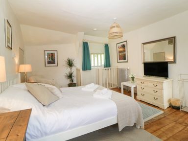 A bedroom with a double bed a dresser with a television and a small table with flowers at The Hideaway at Burrow Hill in Ottery St Mary