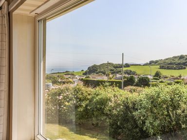 A window view showing bushes gardens houses street lamp posts and green hills at Ty Bedw in Benllech