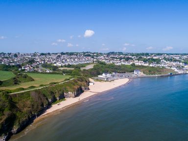 A coastal town with sandy beach green cliffs and houses by the sea at Ty Bedw in Benllech