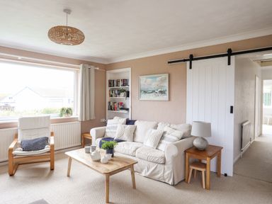A living room with a white sofa and wooden coffee table near a window at Ty Bedw in Benllech
