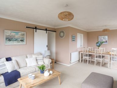 A living room with a sofa cushions and a coffee table next to a dining table with chairs at Ty Bedw in Benllech