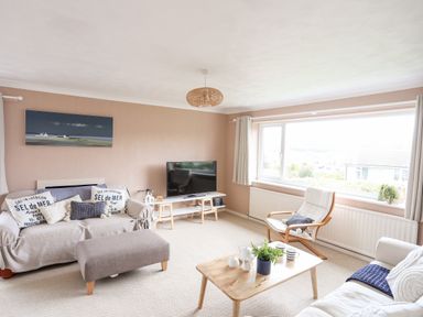 A living room with sofas a coffee table a large window and a television at Ty Bedw in Benllech