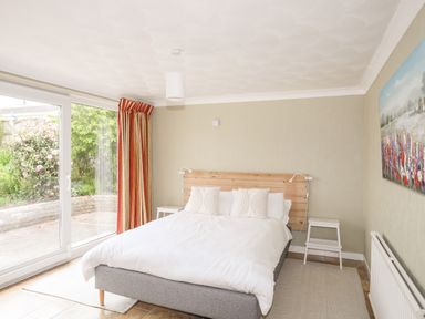 A bedroom with a double bed next to sliding glass doors and two nightstands with lamps at Ty Bedw in Benllech
