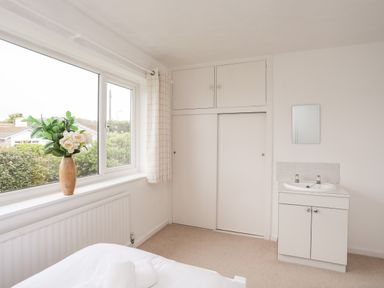A bedroom corner with a window flower vase wardrobe and a sink at Ty Bedw in Benllech
