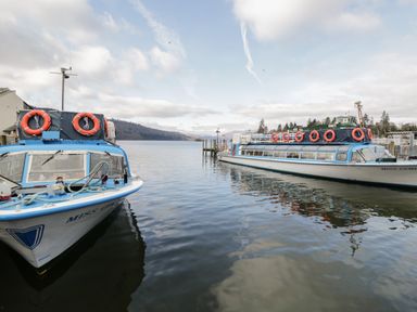 Two passenger boats docked on a lake with hills and trees in the background at Cherry Tree Lodge in Calgarth 37 White Cross Bay near Windermere