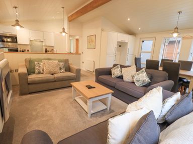 A living room with sofas and a coffee table next to a kitchen and dining area at Cherry Tree Lodge Calgarth 37 White Cross Bay near Windermere