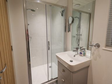 A bathroom with a shower enclosure a sink with a cabinet and a mirror at Cherry Tree Lodge Calgarth 37 White Cross Bay near Windermere