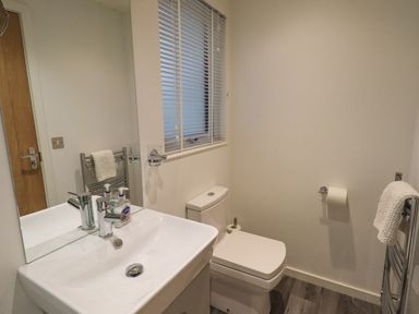 A bathroom with a sink a mirror a toilet a window with blinds and towel racks at Cherry Tree Lodge Calgarth 37 White Cross Bay near Windermere