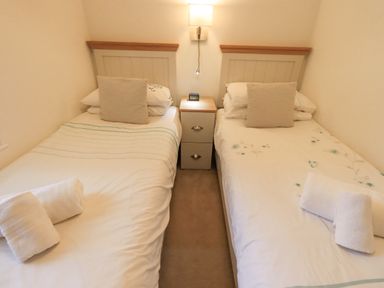 A bedroom with two single beds separated by a nightstand and lamp at Cherry Tree Lodge Calgarth 37 White Cross Bay near Windermere