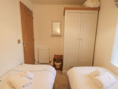 A bedroom with two single beds a wardrobe a wooden door a wall mirror and a window with blinds at Cherry Tree Lodge Calgarth 37 White Cross Bay near Windermere